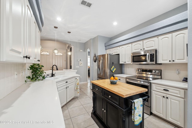 kitchen featuring stainless steel appliances, wood counters, pendant lighting, white cabinets, and sink