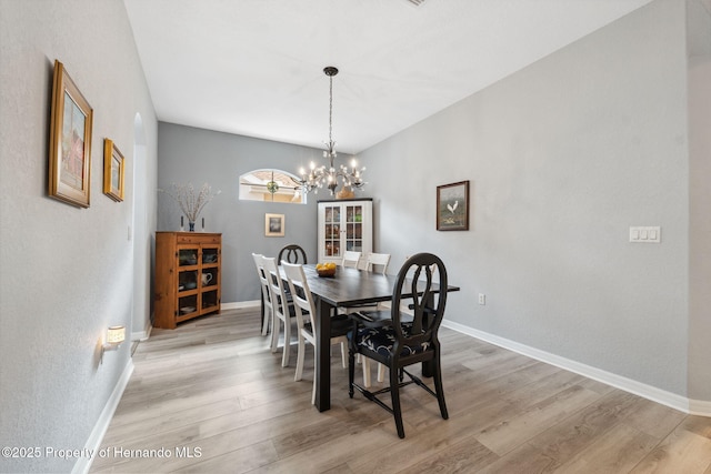 dining space with light wood-type flooring and a notable chandelier