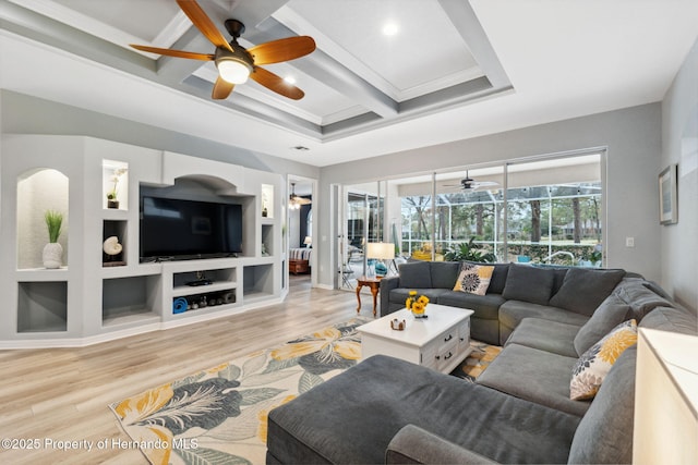 living room with coffered ceiling, built in shelves, light wood-type flooring, crown molding, and beamed ceiling