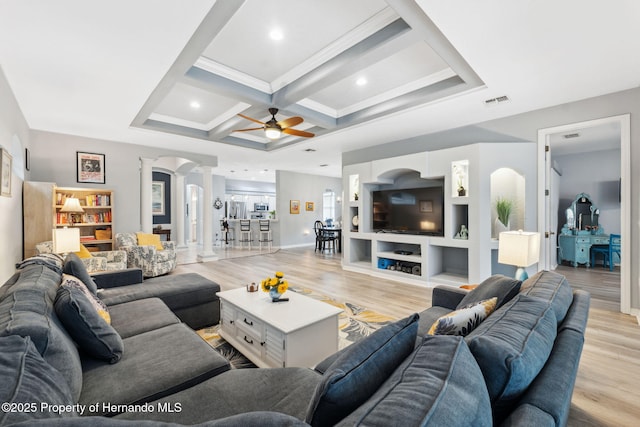 living room featuring coffered ceiling, beamed ceiling, ceiling fan, light hardwood / wood-style flooring, and built in shelves