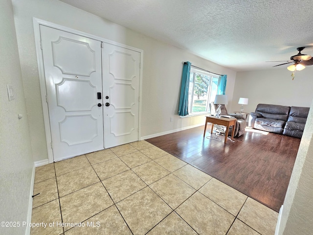 tiled foyer entrance with a textured ceiling and ceiling fan