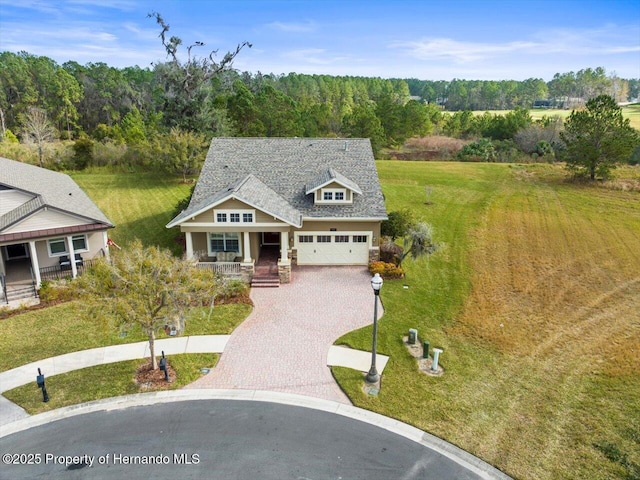 view of front of property featuring covered porch, a front yard, and a garage