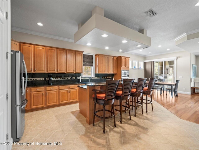 kitchen with a center island, stainless steel appliances, a kitchen bar, crown molding, and sink