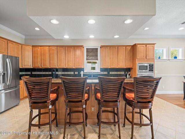 kitchen with appliances with stainless steel finishes, crown molding, and a kitchen island