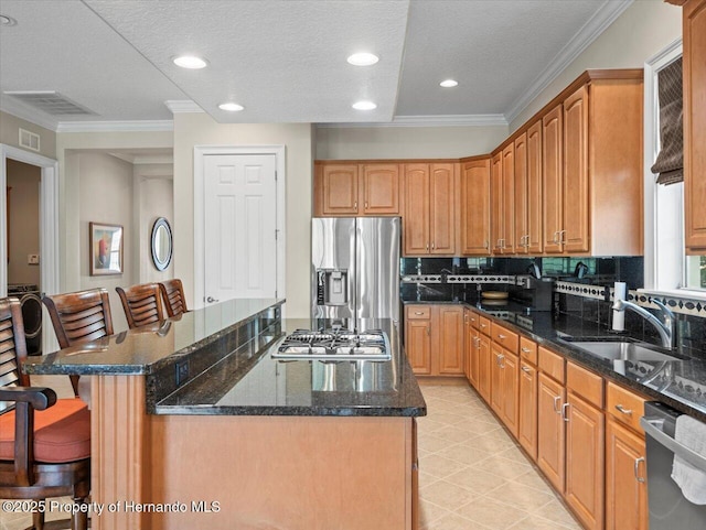 kitchen featuring a center island, a kitchen bar, dark stone counters, appliances with stainless steel finishes, and sink