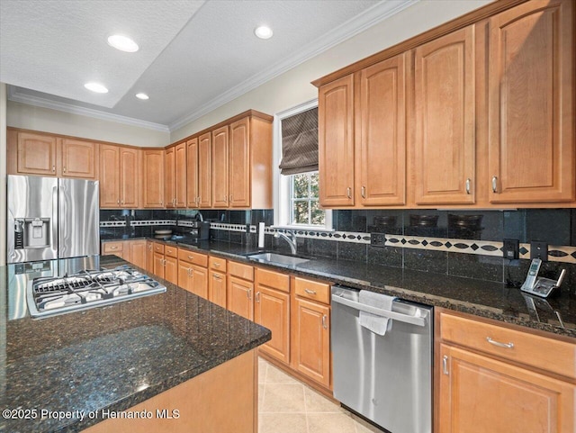 kitchen with dark stone countertops, stainless steel appliances, ornamental molding, sink, and tasteful backsplash