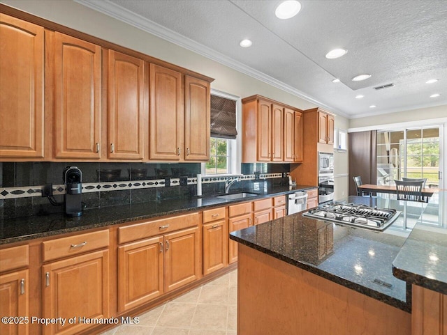 kitchen with stainless steel appliances, dark stone counters, crown molding, and sink