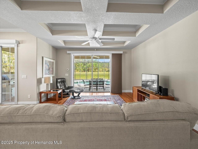 living room featuring hardwood / wood-style flooring, ceiling fan, crown molding, and coffered ceiling