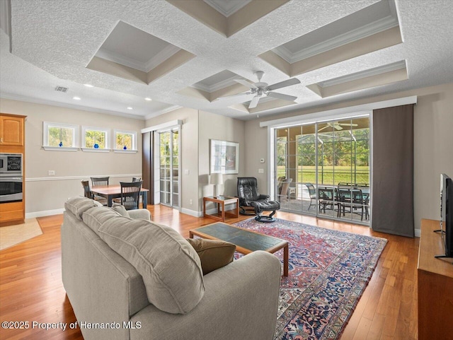 living room featuring a healthy amount of sunlight, coffered ceiling, crown molding, and beamed ceiling