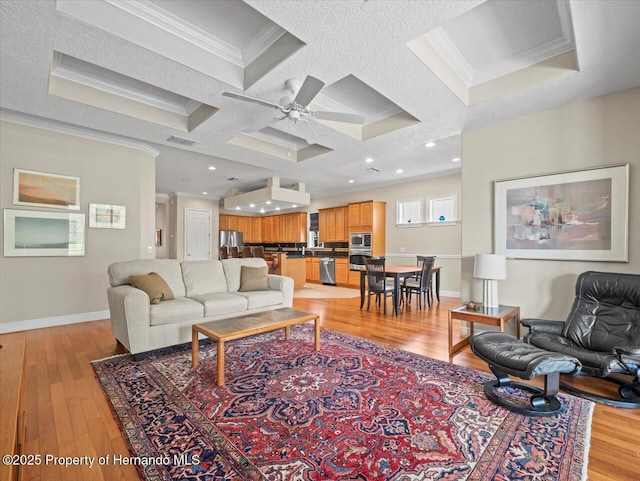 living room featuring ornamental molding, ceiling fan, light hardwood / wood-style flooring, and coffered ceiling