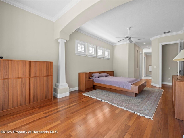 bedroom featuring a textured ceiling, ornate columns, ceiling fan, hardwood / wood-style flooring, and ornamental molding