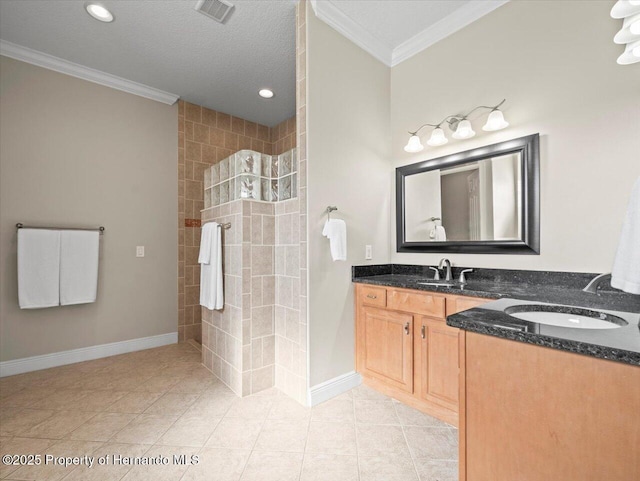 bathroom featuring tile patterned flooring, crown molding, vanity, a tile shower, and a textured ceiling