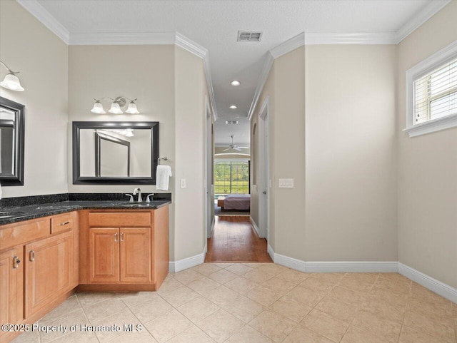 bathroom featuring a healthy amount of sunlight, ornamental molding, and vanity