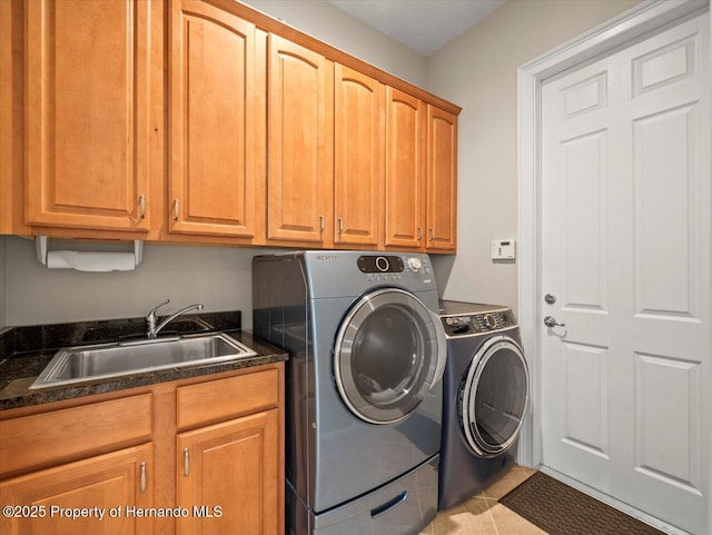 clothes washing area featuring sink, light tile patterned flooring, washer and clothes dryer, and cabinets