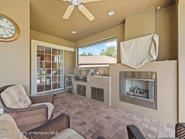 view of patio / terrace featuring exterior kitchen, ceiling fan, and an outdoor fireplace