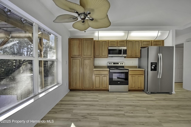 kitchen with light wood-type flooring, ceiling fan, and appliances with stainless steel finishes