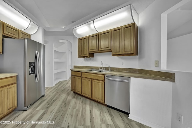 kitchen with stainless steel appliances, built in shelves, light hardwood / wood-style floors, and sink