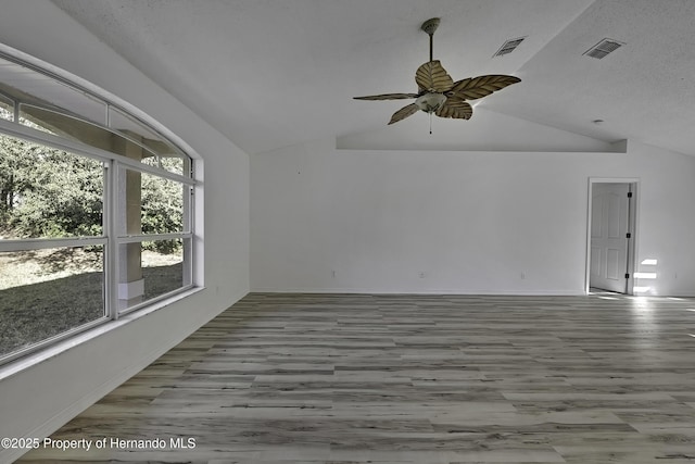 empty room featuring lofted ceiling, a textured ceiling, ceiling fan, and light hardwood / wood-style flooring