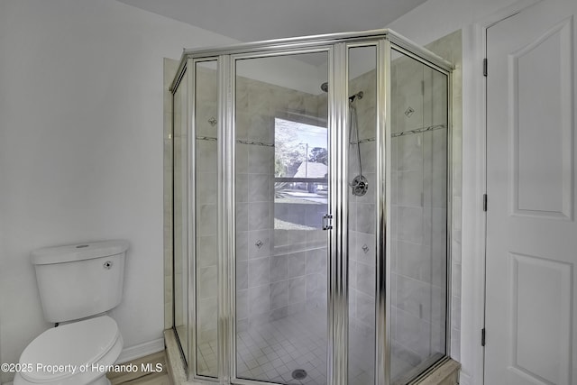 bathroom with toilet and a shower with shower door