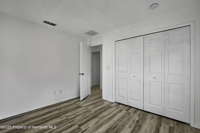 unfurnished bedroom with a closet and hardwood / wood-style flooring