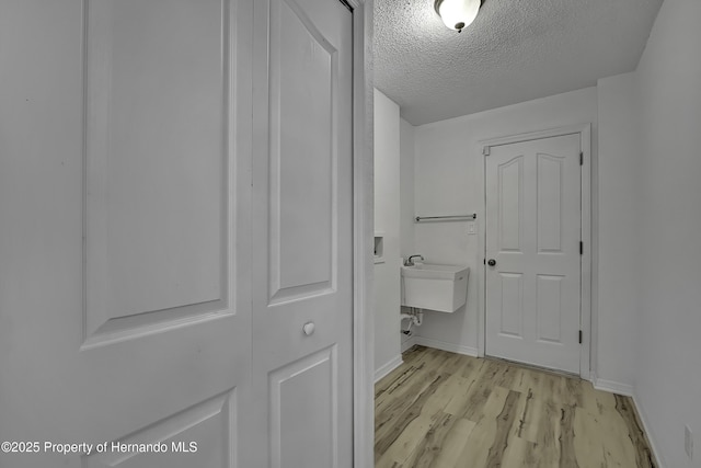 interior space with a textured ceiling, wood-type flooring, and sink