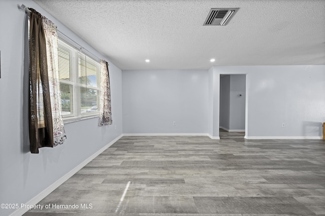 unfurnished room with a textured ceiling and light hardwood / wood-style floors