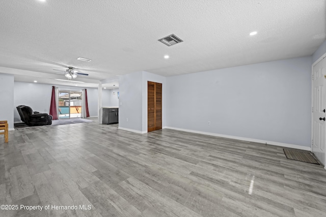 unfurnished living room featuring light hardwood / wood-style floors, a textured ceiling, and ceiling fan