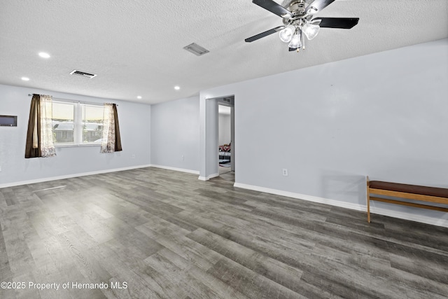 empty room with ceiling fan, dark wood-type flooring, and a textured ceiling