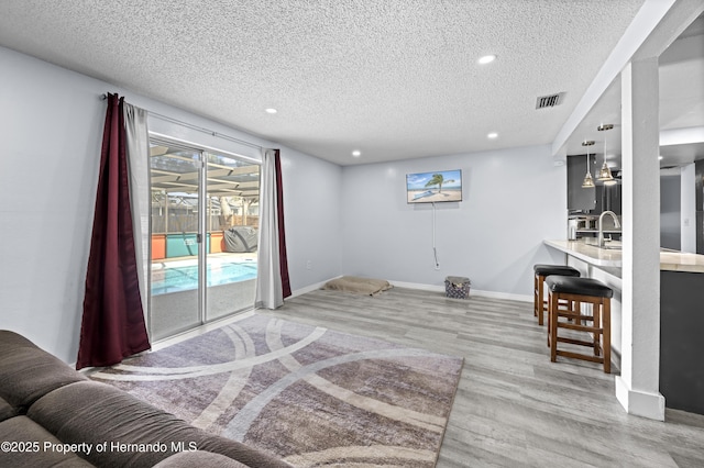 interior space with sink, a textured ceiling, and light hardwood / wood-style flooring