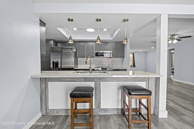 kitchen featuring decorative light fixtures, kitchen peninsula, a kitchen bar, sink, and stainless steel appliances