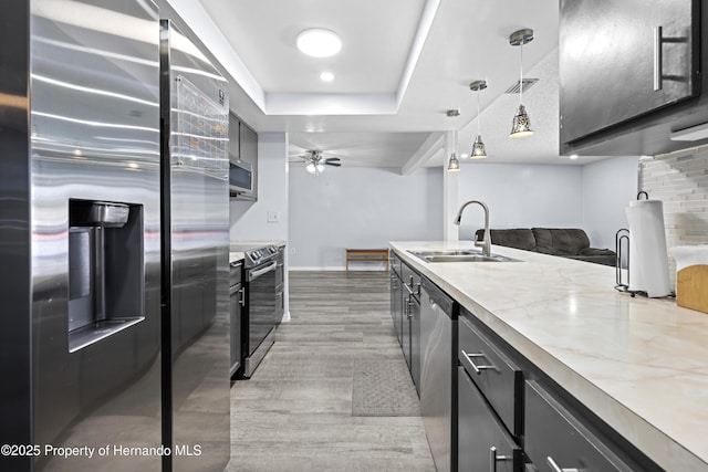 kitchen with ceiling fan, pendant lighting, sink, light stone countertops, and appliances with stainless steel finishes