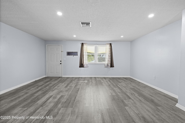 spare room with a textured ceiling and dark wood-type flooring