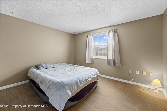 bedroom with a textured ceiling and hardwood / wood-style flooring