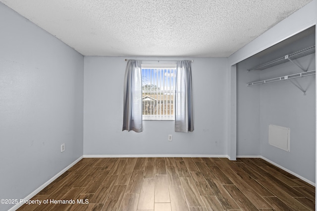 unfurnished bedroom with a closet, dark hardwood / wood-style floors, and a textured ceiling