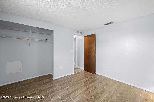 unfurnished bedroom with a closet, a textured ceiling, and wood-type flooring