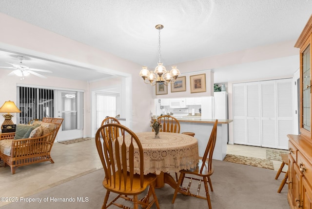 dining space with ceiling fan with notable chandelier and a textured ceiling