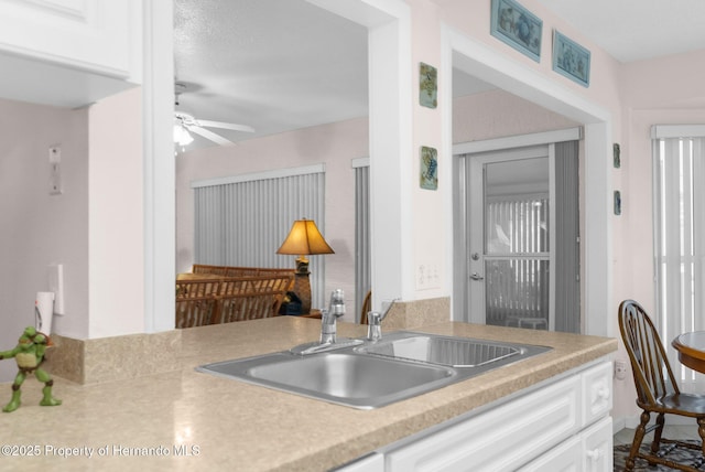 kitchen with sink, a textured ceiling, ceiling fan, and white cabinetry