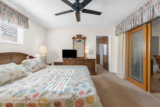 bedroom with ceiling fan, light colored carpet, and a textured ceiling