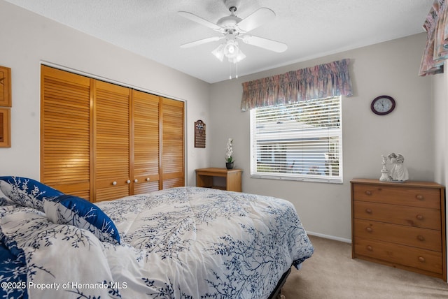 bedroom with ceiling fan, a closet, light carpet, and a textured ceiling