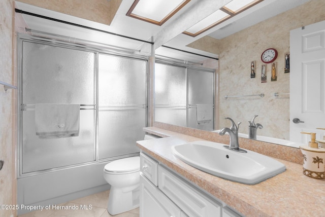 full bathroom featuring toilet, vanity, tile patterned floors, and bath / shower combo with glass door