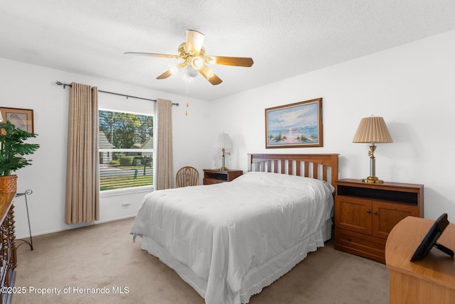 bedroom with ceiling fan, light colored carpet, and a textured ceiling