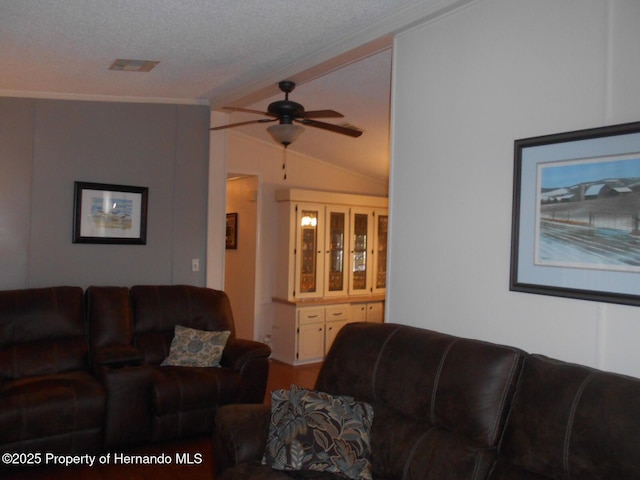 living room with a textured ceiling, ceiling fan, ornamental molding, and vaulted ceiling