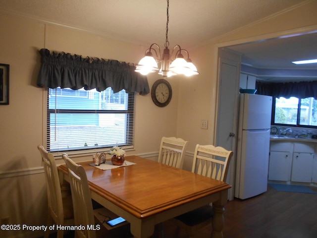 dining area featuring lofted ceiling, an inviting chandelier, wood-type flooring, and sink