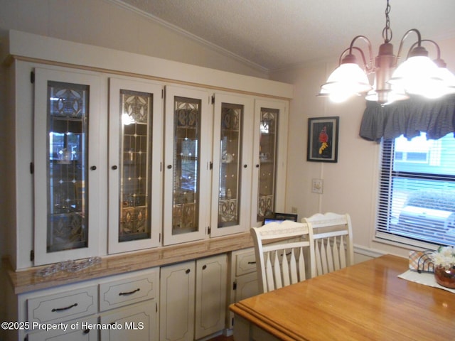 dining room with ornamental molding, an inviting chandelier, and vaulted ceiling