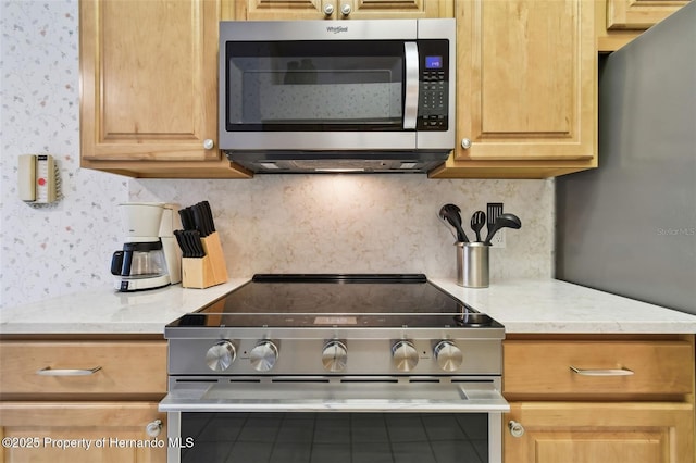 kitchen with appliances with stainless steel finishes, light stone counters, and tasteful backsplash