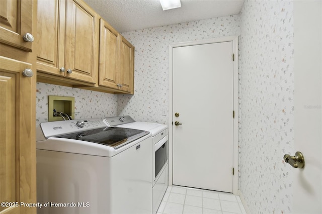 laundry area with light tile patterned flooring, a textured ceiling, cabinets, and separate washer and dryer