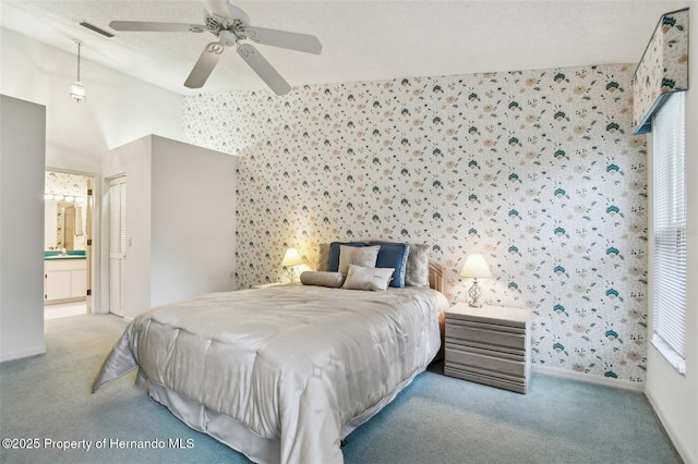 bedroom featuring sink, ensuite bathroom, light carpet, ceiling fan, and a closet