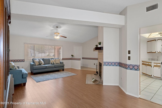 living room featuring ceiling fan, vaulted ceiling, and light hardwood / wood-style floors