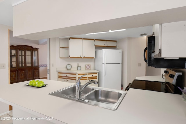 kitchen with white fridge, stainless steel range with electric stovetop, white cabinets, sink, and kitchen peninsula