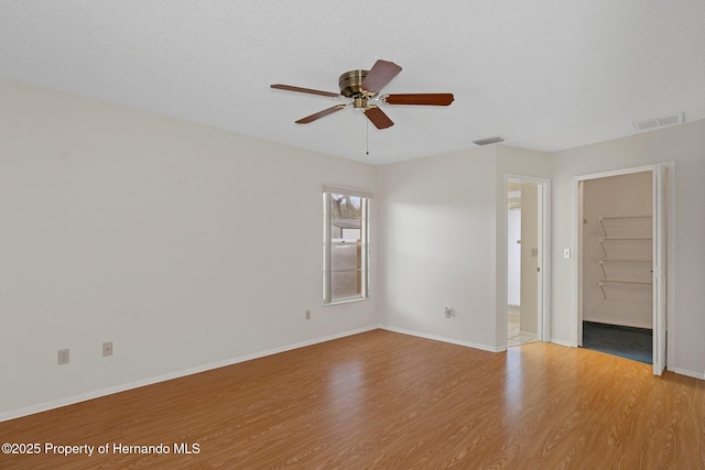 empty room featuring ceiling fan, light hardwood / wood-style flooring, and a textured ceiling